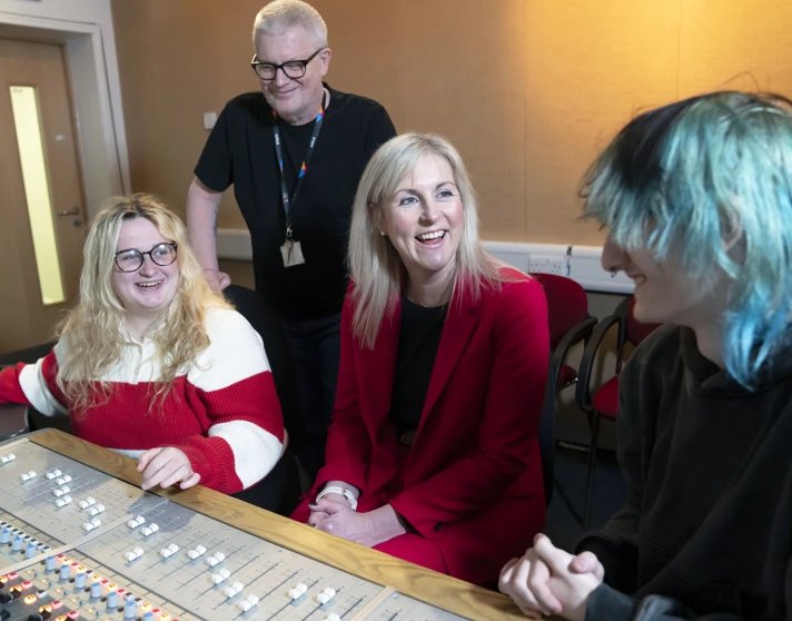 Principal Joanna Campbell chats with students and a staff member in a Glasgow Kelvin College recording studio, all smiling around a sound mixing desk. Principal Joanna Campbell chats with students and a staff member in a Glasgow Kelvin College recording studio, all smiling around a sound mixing desk.